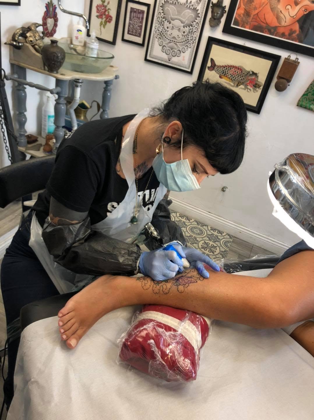 L’artista di The Ten Bells realizza un tatuaggio sulla gamba di una cliente nello studio